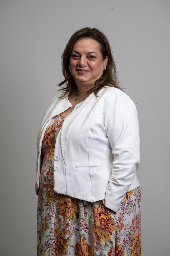 Headshot of DonateLife Victoria staff member Toula Saltas wearing a white blazer over a patterned orange dress