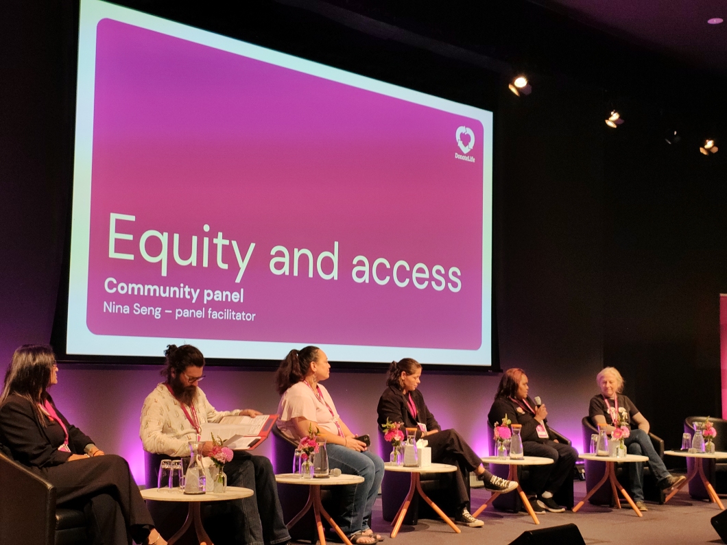 A community panel discussion on ‘Equity and Access’ featuring multiple speakers and a screen displaying the event title and facilitator’s name.