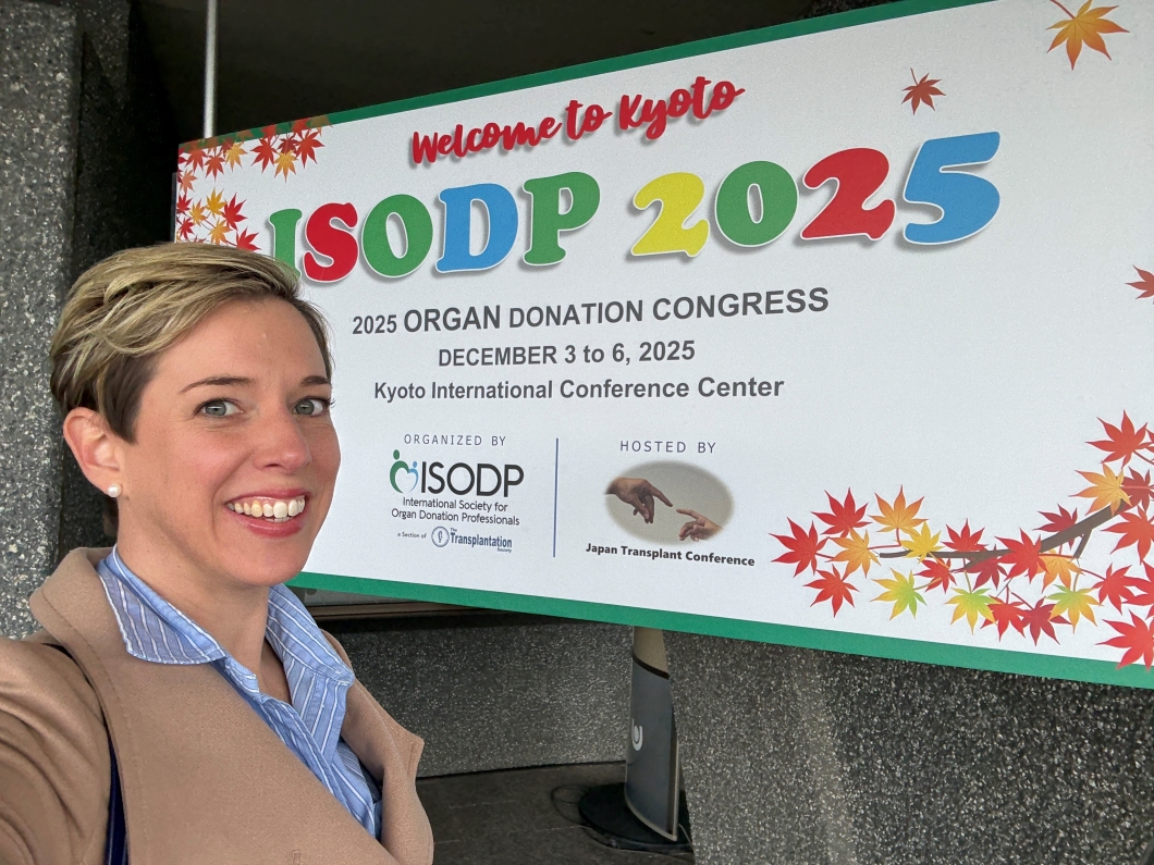A person stands in front of a large sign for the ‘ISODP 2025 Organ Donation Congress’ at the Kyoto International Conference Center. The sign features colourful lettering, autumn leaf graphics, and logos for the International Society for Organ Donation Professionals and the Japan Transplant Conference.