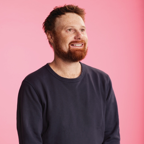 Aaron pictured in front of a pink backdrop