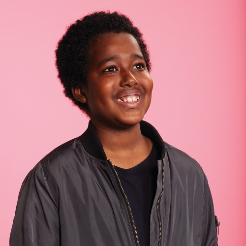 Hussein pictured in front of a pink backdrop