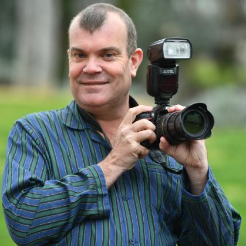 Corneal recipient Adam holding his camera and posing for a photo.