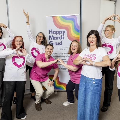 NSW Organ and Donation Services team wearing DonateLife shirts in front of an LGBTQI+ banner