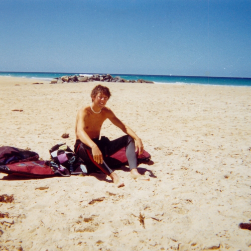 Young man sitting on the sandy beach 
