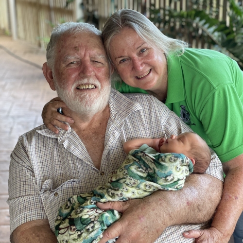 Peter and his wife Judy smile while holding their grandchild after Peter's kidney transplant